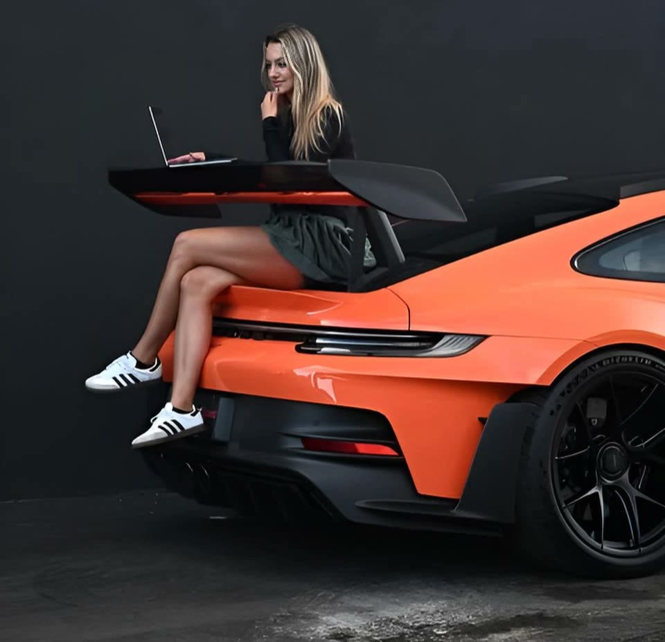 Claudia on the wing of an orange Porsche GT3 RS